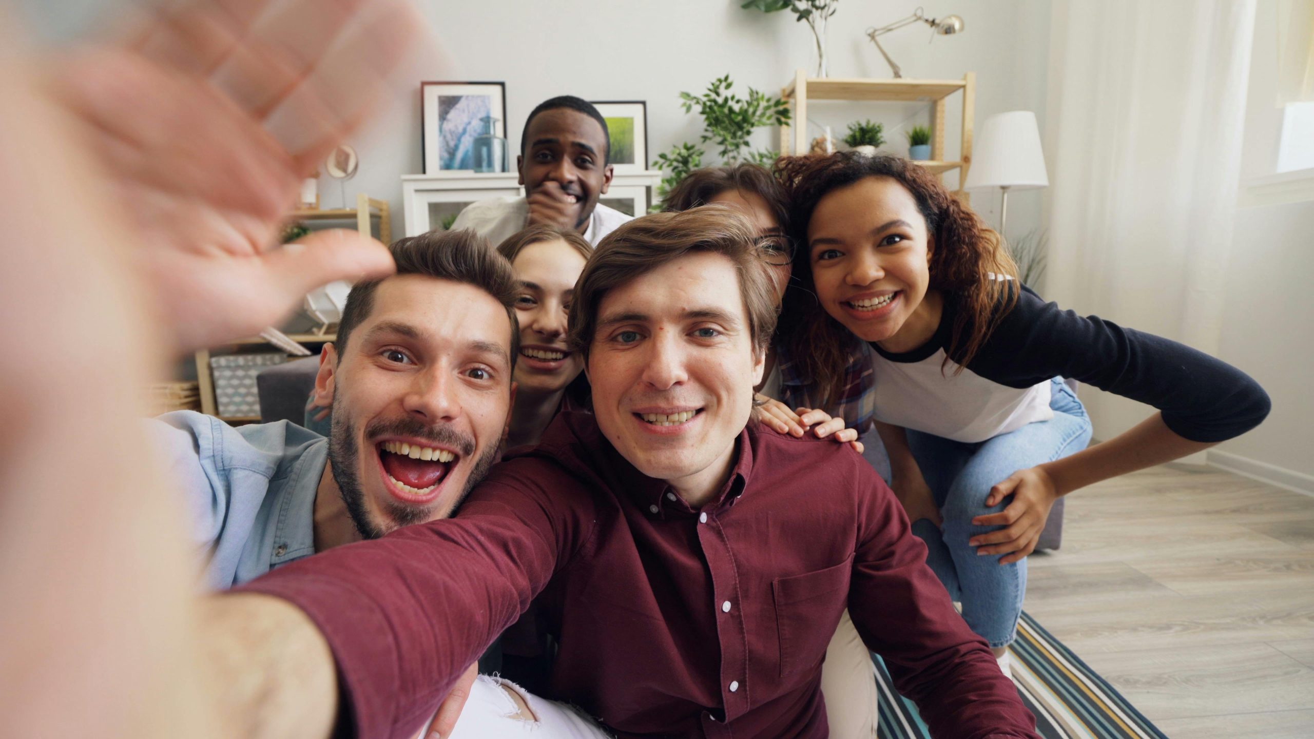 Gruppo di giovani si scatta un selfie. Sono 6 persone, in abiti casual, in primissimo piano si vedono le mani e il braccio di chi scatta la foto, poi i visi del gruppo.